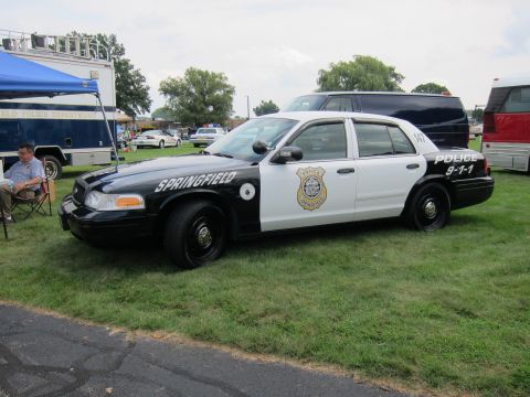 1991 Ford LTD Crown Victoria - black-and-white Ford Crown Victoria marked Springfield Police 9-1-1, number 147, parked on grass beside a command trailer.