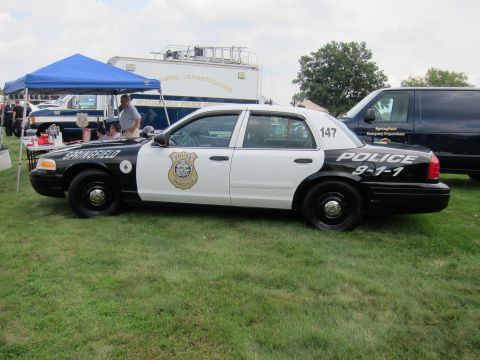 1991 Ford LTD Crown Victoria - black-and-white Ford Crown Victoria marked Springfield Police 9-1-1, number 147, sits on grass beside a tent and command trailer.