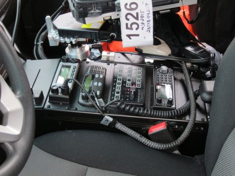 1991 Ford LTD Crown Victoria - police vehicle console packed with stacked two-way radios and control heads, topped by a handwritten placard reading 1526.