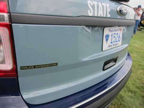 1991 Ford LTD Crown Victoria - Detail of a two-tone blue Ford police SUV tailgate showing a Police Interceptor emblem and a Massachusetts State Trooper plate reading 1526.