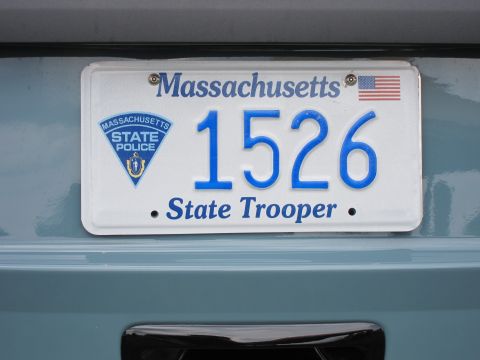 1991 Ford LTD Crown Victoria - Close-up of a white Massachusetts State Trooper license plate numbered 1526, featuring the state police triangular seal and a small US flag.