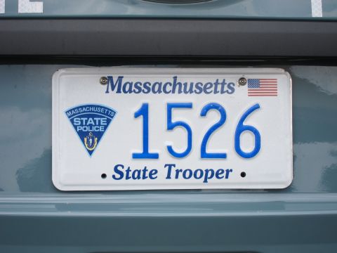 1991 Ford LTD Crown Victoria - white Massachusetts State Trooper license plate reading 1526 with state police seal, bolted to a light-blue painted vehicle surface.