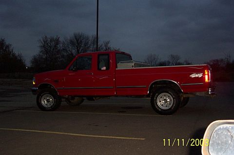 1978 Ford Bronco - A red pickup truck is parked in a lot at dusk, equipped with a toolbox in the bed.