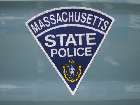 1991 Ford LTD Crown Victoria - reflective triangular Massachusetts State Police emblem bearing the state seal, applied to a teal-blue painted vehicle panel.