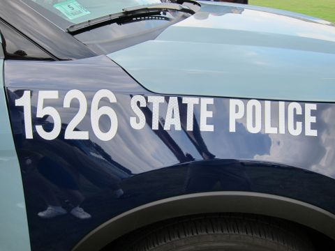 1991 Ford LTD Crown Victoria - Reflective white lettering reading 1526 STATE POLICE across the dark-blue front fender and hood of a police SUV on grass.