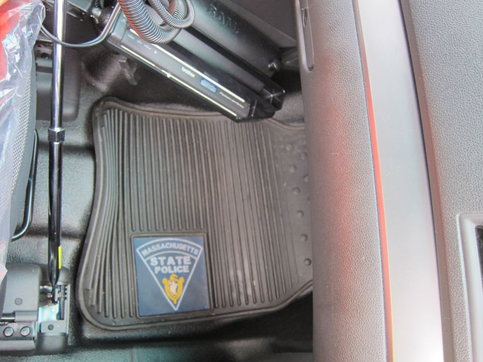 Vehicle floor area with rubber Massachusetts State Police logo mat and mounted laptop equipment