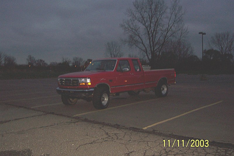 Red Ford F-150 pickup truck parked in a lot at dusk