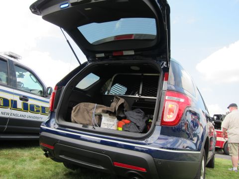 1991 Ford LTD Crown Victoria - dark-blue Ford Explorer police SUV photographed from the rear with its hatch open and cargo visible, at an outdoor gathering on grass.