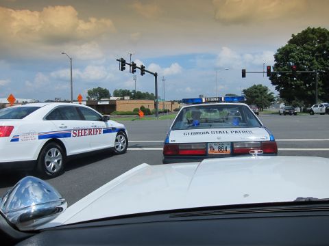 1991 Ford LTD Crown Victoria - Through a windshield, a white SHERIFF sedan and a Georgia State Patrol cruiser numbered 864 wait at a multi-light intersection.