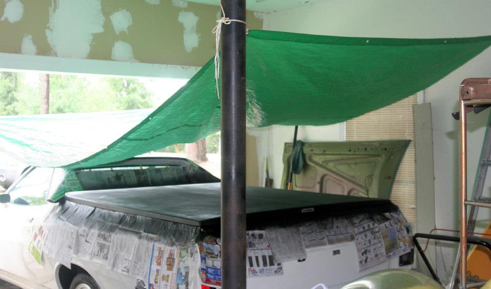 1976 Ford Ranchero with bed cover, rear view, partially covered in newspaper
