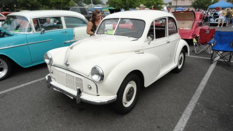 1964 Ford Fairlane - A white Morris Minor is parked at an outdoor car show next to other classic vehicles.