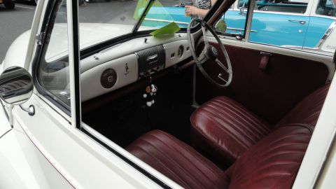 1964 Ford Fairlane - Interior view of a classic car with burgundy seats and dashboard, alongside another vehicle.