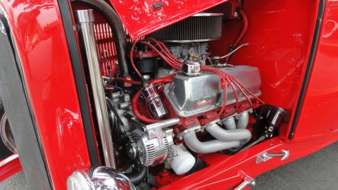 1964 Ford Fairlane - The engine bay of a classic car, showing a V8 engine with red spark plug wires and a chrome air cleaner.
