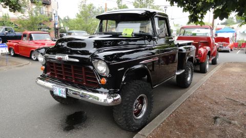 1964 Ford Fairlane - A black pickup truck with a distinctive grille is parked alongside other vehicles.