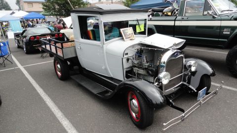 1964 Ford Fairlane - A 1929 Ford Model A pickup truck is displayed at an outdoor event, with a Corvette nearby.