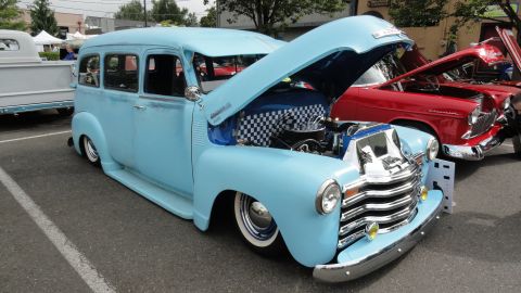 1964 Ford Fairlane - Custom light blue Chevrolet Suburban parked next to a red car at a show.