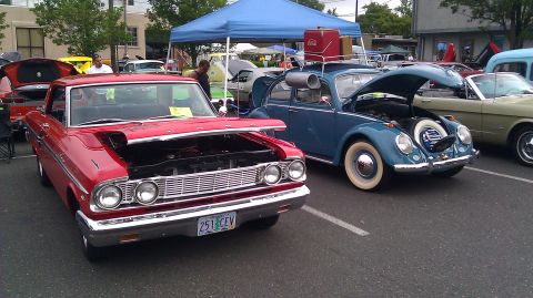 1964 Ford Fairlane - Two classic cars, a red 1964 Ford Fairlane and a blue VW Beetle, are displayed with their hoods open at an outdoor event.