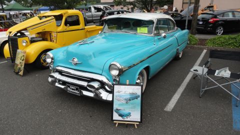 1964 Ford Fairlane - A turquoise 1953 Oldsmobile is displayed next to a yellow pickup truck at an outdoor event.