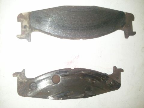 1994 Ford Bronco - Worn brake pads show signs of heavy use and damage.