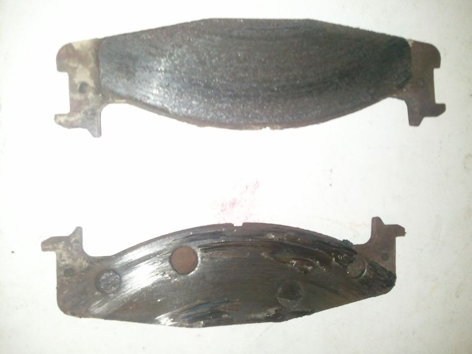 Two worn brake pads, one with significant scoring and missing material