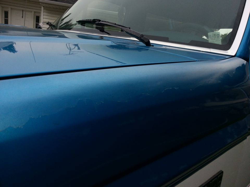 Blue SUV hood with peeling paint, close-up angle showing windshield wiper