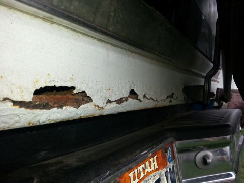 1994 Ford Bronco - Severe rust perforation on the rocker panel of a vehicle, with a Utah license plate in view.