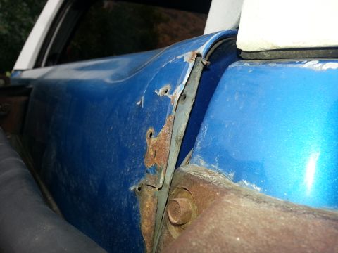1994 Ford Bronco - The door hinge area shows significant rust and damage.
