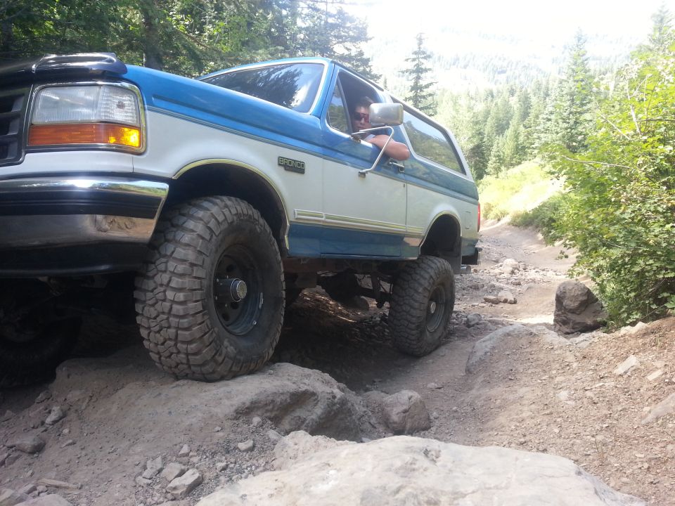 Ford Bronco driving over rocks on a dirt trail