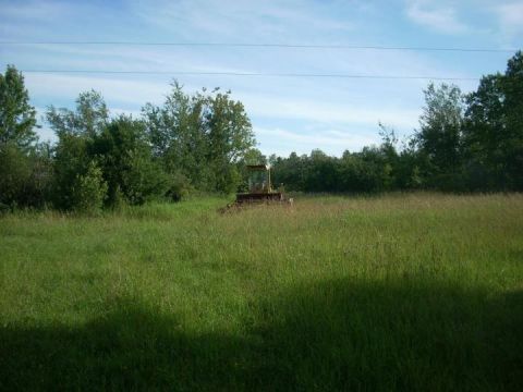 1987 Ford F-250 - A bulldozer sits in a field of tall grass under a partly cloudy sky.