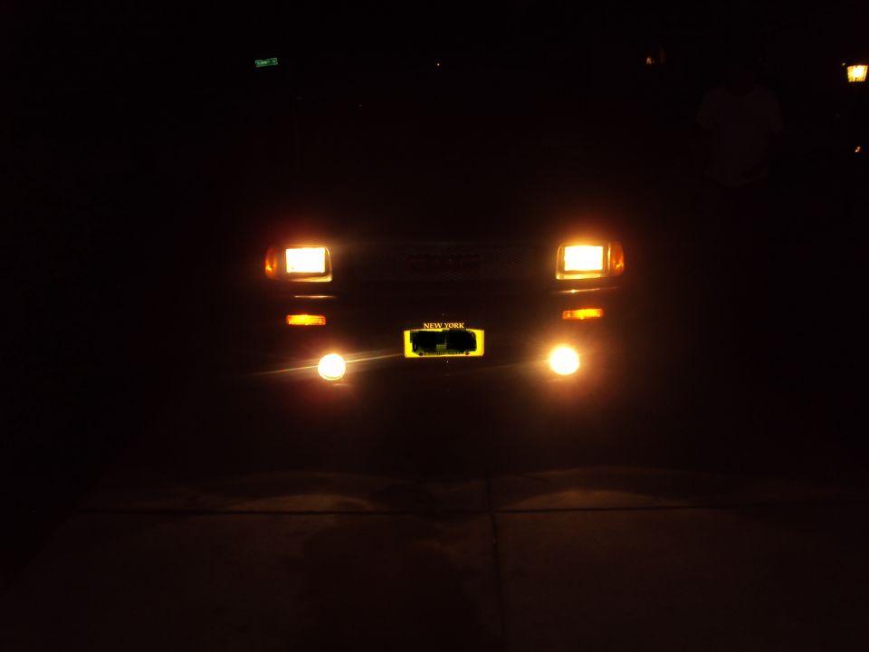 Front view of truck at night with headlights and fog lights on, New York plate visible