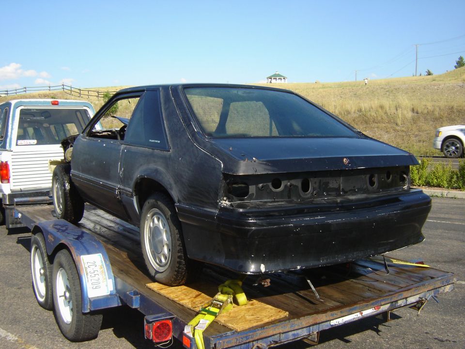black 1987 Ford Mustang on trailer, missing taillights and bumper