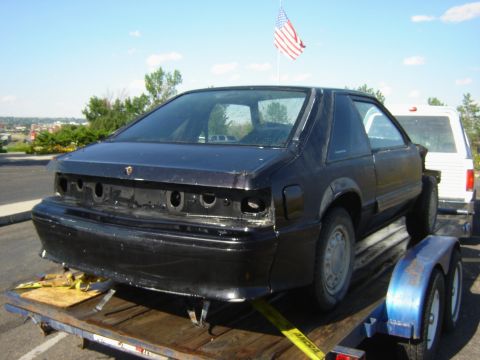 1987 Ford Mustang - A black 1987 Ford Mustang coupe is seen on a trailer, viewed from the rear.