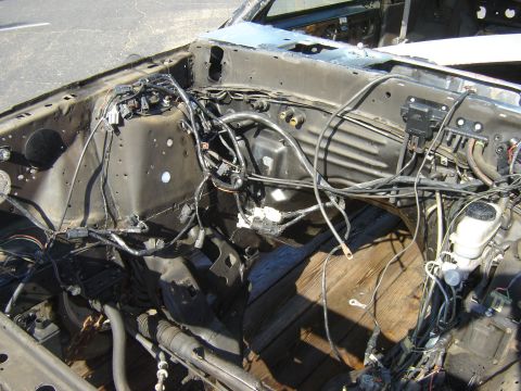 1987 Ford Mustang - The engine bay of a 1987 Ford Mustang shows exposed wiring and a wooden floor, suggesting a custom build or restoration project.