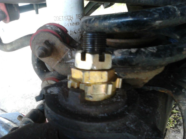 Jack the wheel up and take the tire off. secure it properly. 

Remove the cotter pin that prevents the nut from vibrating loose. Take the nut off.