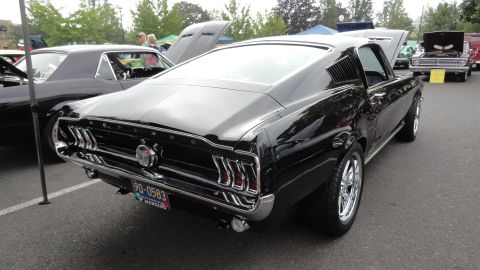 1964 Ford Fairlane - A black 1967 Ford Mustang fastback is parked at an outdoor event, with other cars visible.