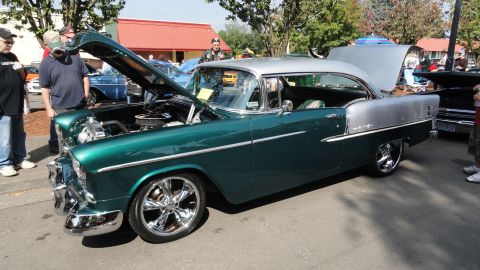 1964 Ford Fairlane - A two-tone green and silver 1955 Chevrolet Bel Air is displayed with its hood up at a car show.