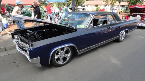 1964 Ford Fairlane - A two-tone blue and gray 1964 Ford Fairlane coupe is displayed with its hood open, custom wheels and a lowered stance.