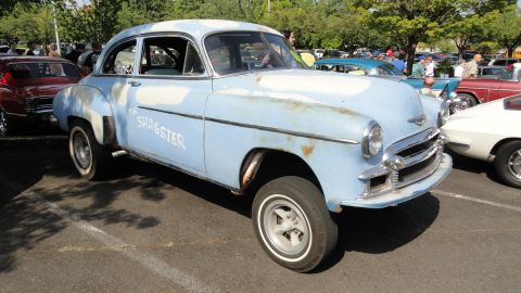 1964 Ford Fairlane - A light blue sedan with primer patches and rust, identified as "THE SHAGSTER", sits in a parking lot.
