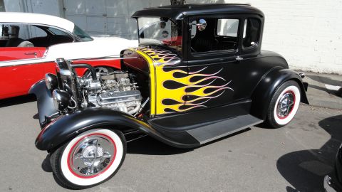1964 Ford Fairlane - Custom hot rod coupe features flame graphics and a powerful V8 engine, parked next to another classic car.