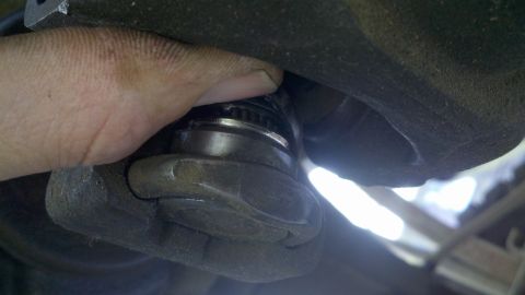 1978 Ford Bronco - Close-up of a hand working on a vehicle's ball joint assembly.