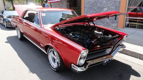 1964 Ford Fairlane - 1965 Pontiac Tempest coupe on display, engine compartment open for viewing.