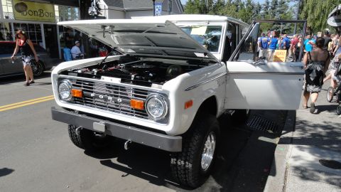 1964 Ford Fairlane - White Ford Bronco on display with hood and door open, showing the engine and interior. The 'FORD' lettering is prominent on the grille.