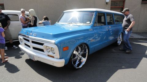 1964 Ford Fairlane - A blue GMC Suburban with a white roof and large chrome wheels is parked outside.