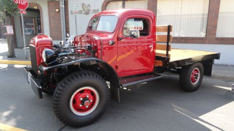 1964 Ford Fairlane - A vintage red flatbed truck is parked on a street, its hood open to reveal the engine.