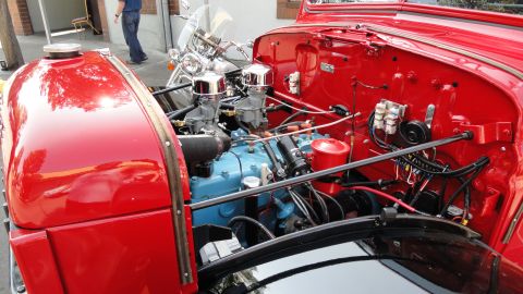 1964 Ford Fairlane - Close-up of a red car's engine bay, a blue engine block and chrome carburetors, with a motorcycle in the background.