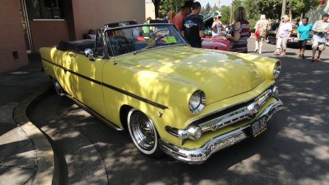 1964 Ford Fairlane - A bright yellow convertible with a chrome grille and whitewall tires is parked on a sunny day.