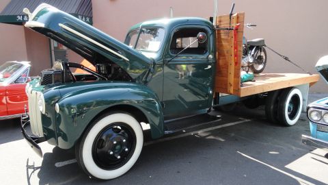 1964 Ford Fairlane - A vintage green flatbed truck is parked with its hood open, revealing the engine compartment.