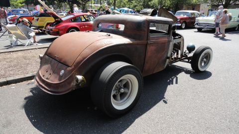 1964 Ford Fairlane - A heavily rusted hot rod coupe is parked outdoors, showing its custom modifications and vintage aesthetic.