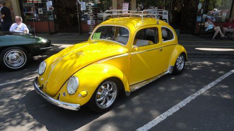 1964 Ford Fairlane - A yellow Volkswagen Beetle is parked on the street, with another vehicle beside it.