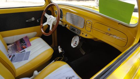 1964 Ford Fairlane - The custom interior features yellow and white two-tone seats, a wood-rimmed steering wheel, and a prominent dashboard gauge.